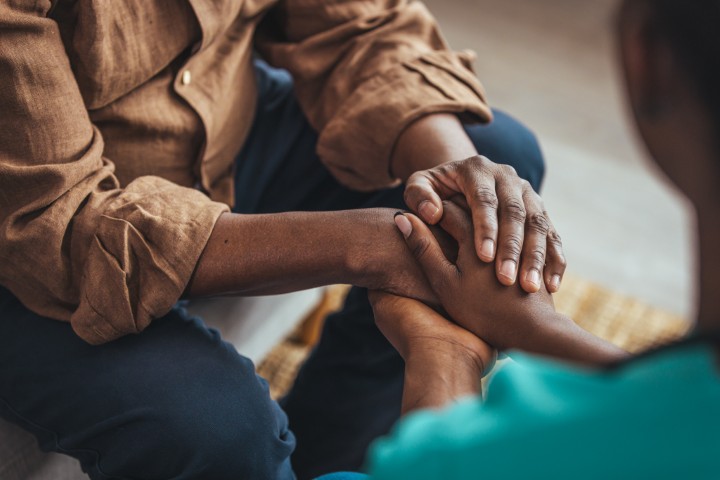 Two people resting hands together in comfort.